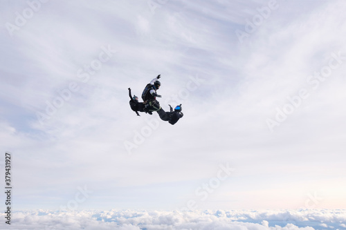 Skydiving. Three skydivers are falling in the cloudy sky.