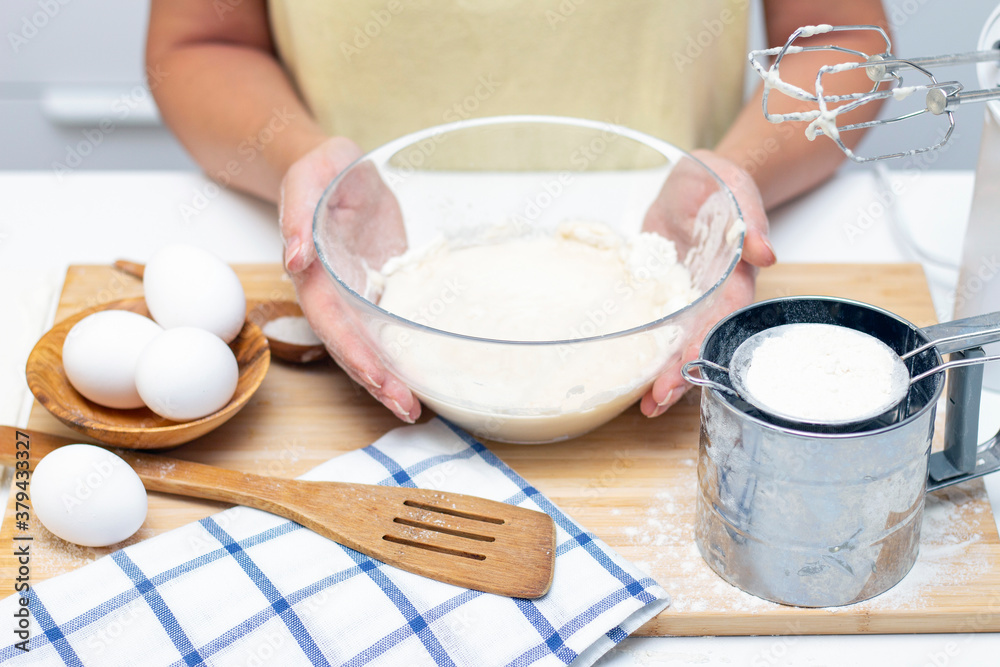 Home cooking concept. Female hands prepare homemade dough on a floured wooden board. Close-up. Home cooking concept. Female hands prepare homemade dough on a floured wooden board. Close-up.