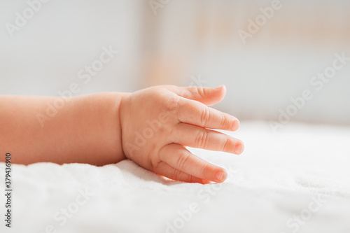 A hand of a baby lying on a white bed. Close-up of the palm. Concept of parenthood and children s day