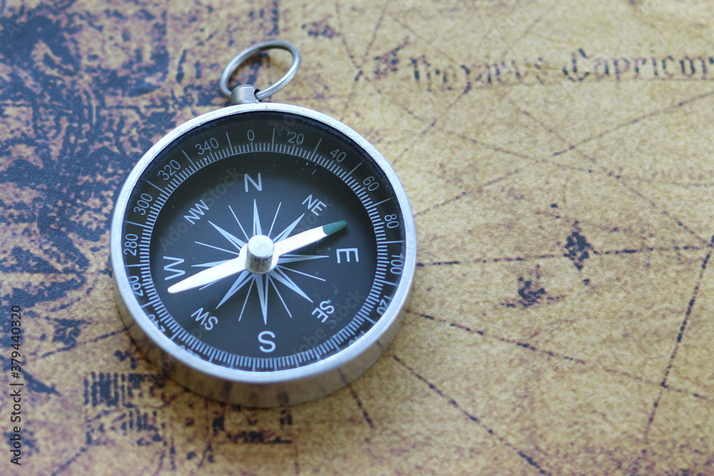 Classic round compass on background of old vintage map of world as symbol of tourism with map and compass, travel with map and compass and outdoor activities with map and compass