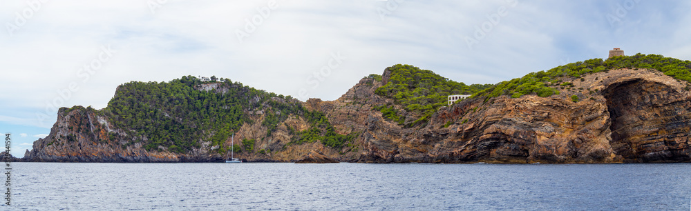 Panoramic scene of the rocky coast of Ibiza in the Balearic islands. Sailboat vacation in coastline in the mediterranean sea.