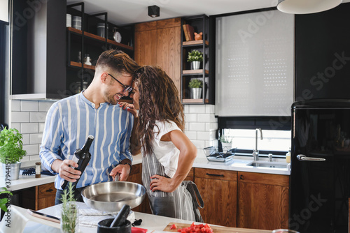 Young cheerful multi ethnic couple preparing pasta together at their modern kitchen