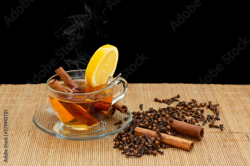 aromatik sıcak tarçın çayı ve ahşap masa üzerinde karanfil tohumları photo