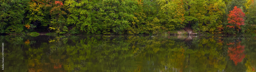 Panoramic view of a picturesque autumn landscape with beautiful trees near the lake