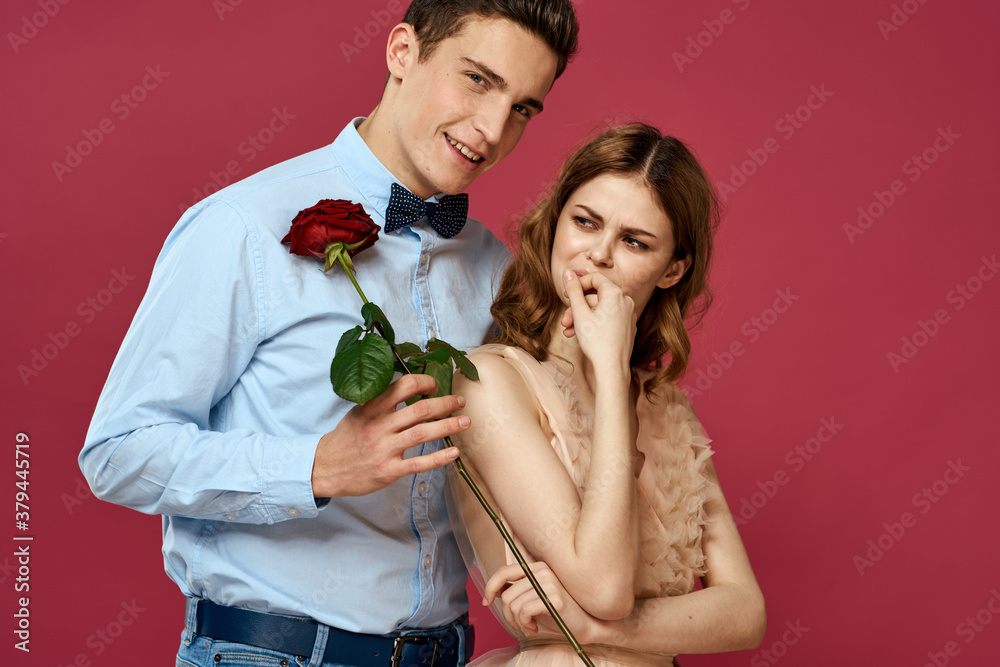 enamored man and woman with a red flower on a pink background hug each other Copy Space enamored man and woman with a red flower on a pink background hug each other Copy Space