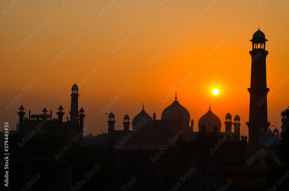 silhouette of a mosque and it's towers and moon with blue and orange warm background