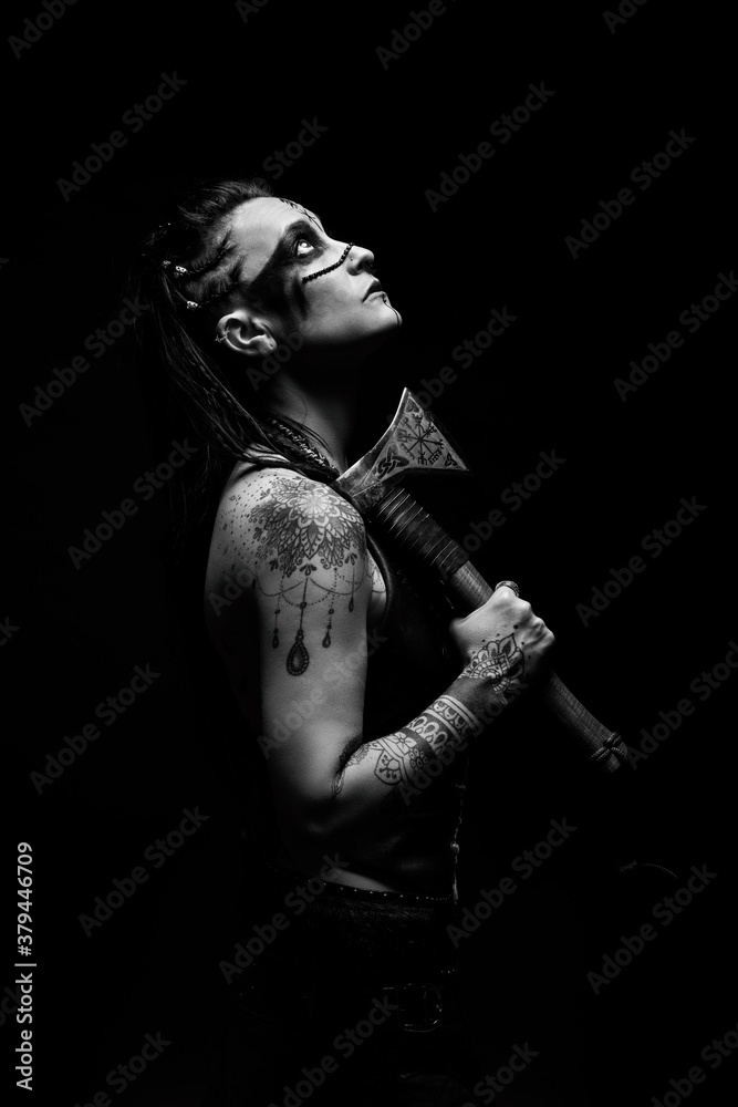 Obraz premium Portrait of a young tattooed Viking warrior with an ax on her shoulder