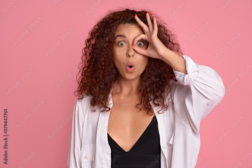Wow awesome. Close-up portrait of speechless impressed woman seeing something stunning, look through okay gesture open mouth wondered, stare fascinated at precious cool thing, pink background