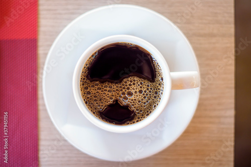top view of cup of hot black coffee on wooden table background