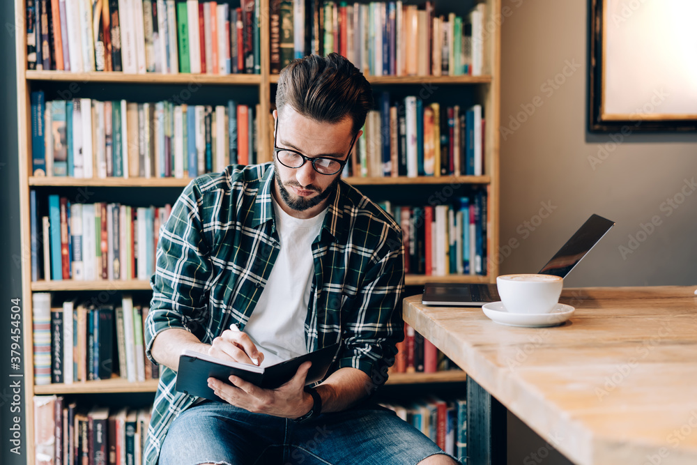 Focused man with diary working in library open space Focused man with diary working in library open space