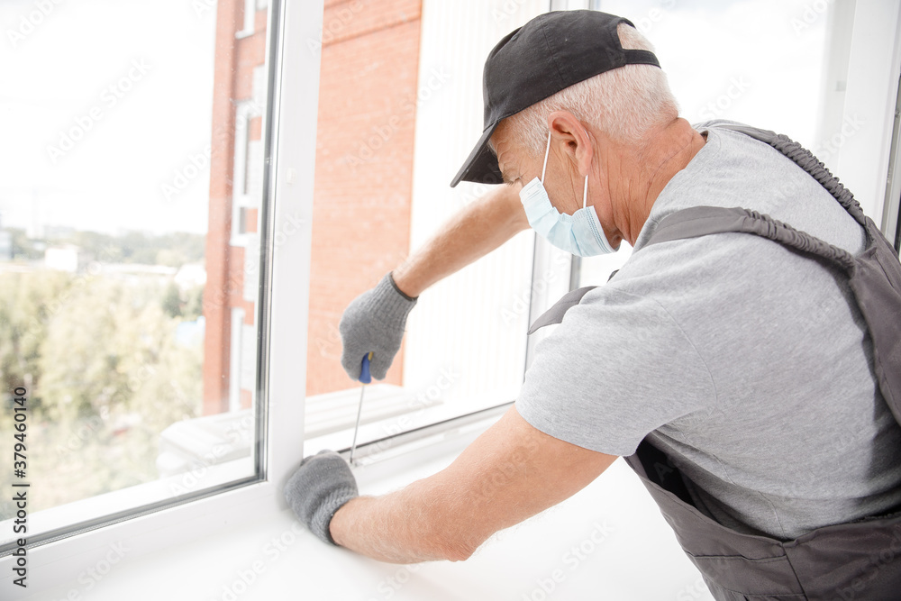 Worker man installs plastic windows and doors with double-glazed white