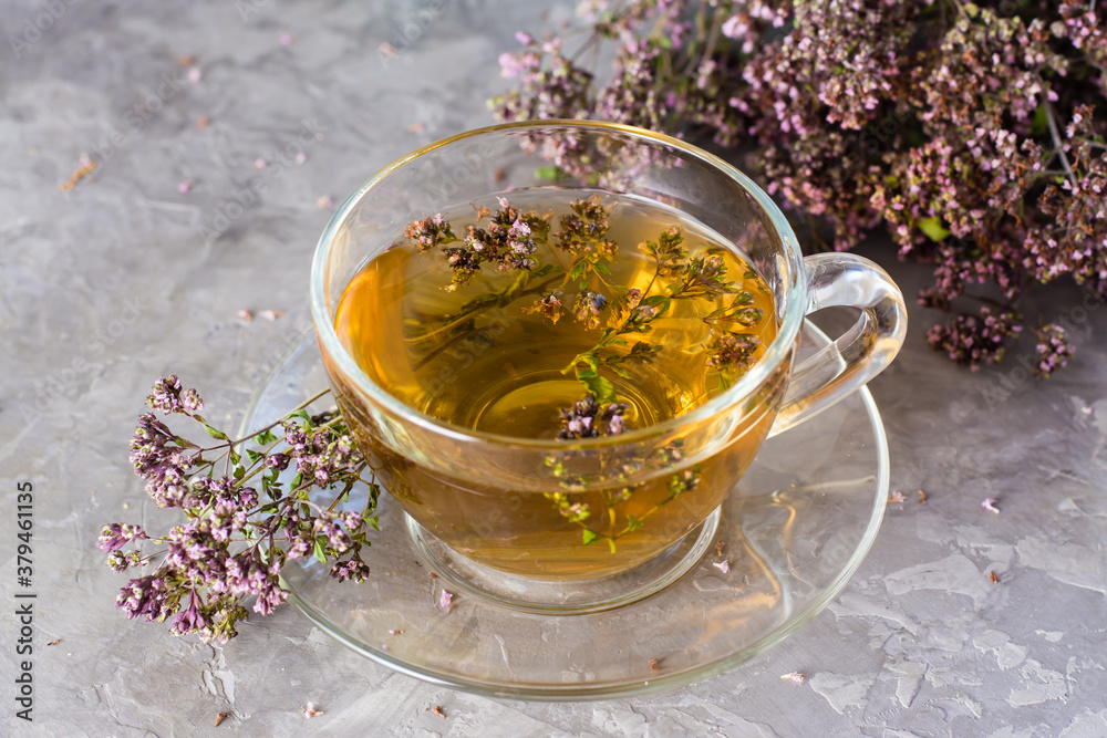 Herbal treatment. Tea with oregano in a cup on the table close-up. Relaxing drink Herbal treatment. Tea with oregano in a cup on the table close-up. Relaxing drink