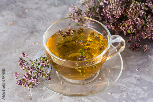Herbal treatment. Tea with oregano in a cup on the table close-up. Relaxing drink