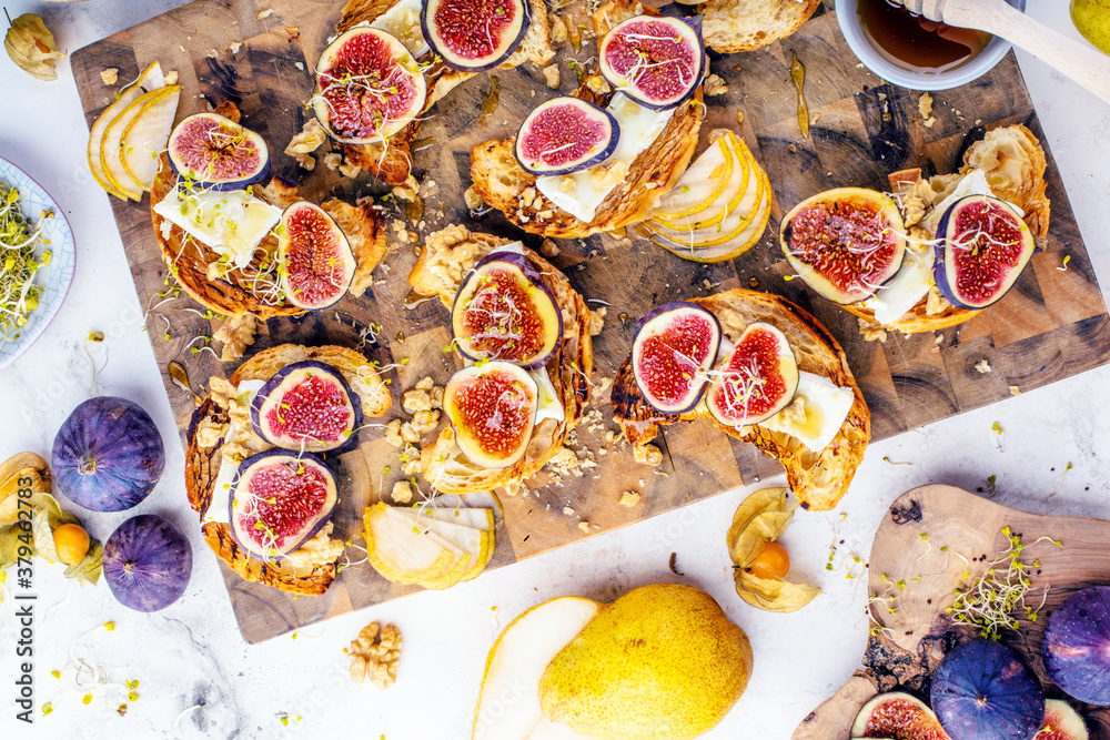 Fototapeta premium view of delicious freshly baked croissants with figs, pears, nuts and honey