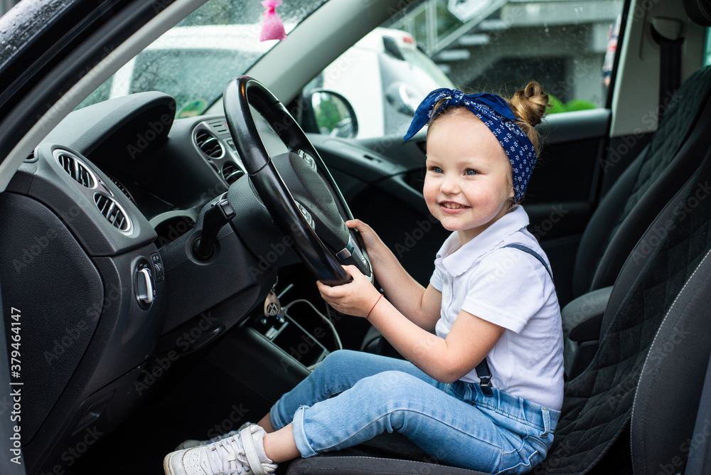 A little girl pretends to drive a car. Concept photo of children education, learning , drive a car,funny, happy, play, happiness, car insurance A little girl pretends to drive a car. Concept photo of children education, learning , drive a car,funny, happy, play, happiness, car insurance