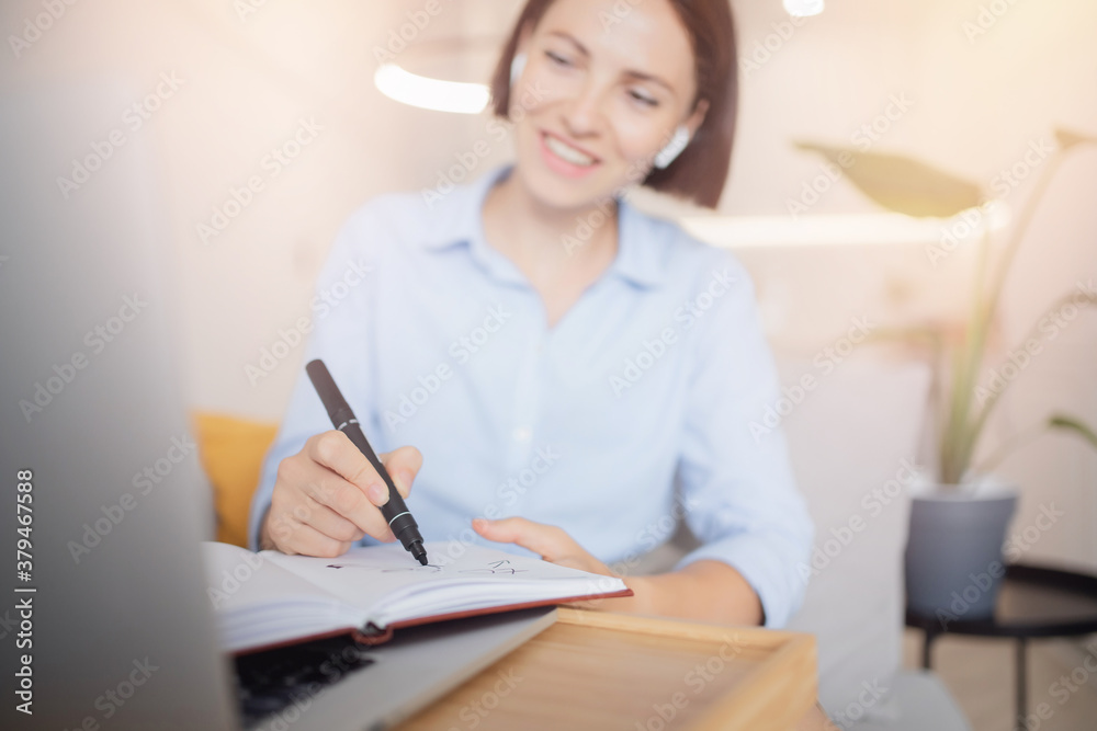 Work from home office, woman smiles and conducts business negotiations with employees via video call internet laptop, light background Work from home office, woman smiles and conducts business negotiations with employees via video call internet laptop, light background
