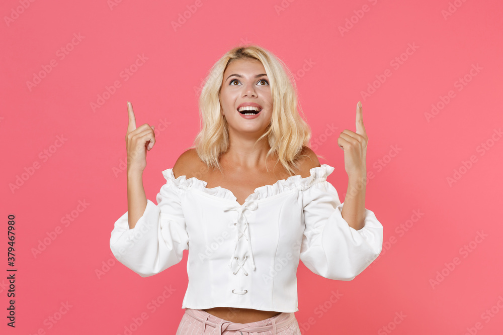 Φωτογραφία Smiling funny cheerful excited young blonde woman 20s in white casual clothes standing pointing index fingers up on mock up copy space isolated on bright pink colour background, studio portrait