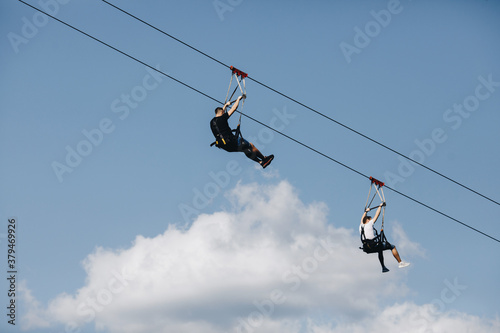 a brave man descends on a zip line high in the mountains above the forest