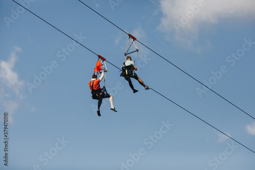 a brave man descends on a zip line high in the mountains above the forest