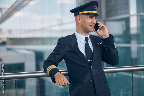 Cheerful male pilot talking on cellphone at airport