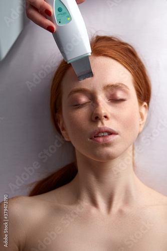 facial skin rejuvenation by microcurrent therapy in cosmetology salon, using special device to perform a facial rejuvenation procedure for attractive caucasian young female