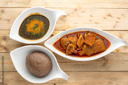 Amala and Ewedu with Assorted meat Stew in ceramic bowls on a wooden surface, Flatlay perspective