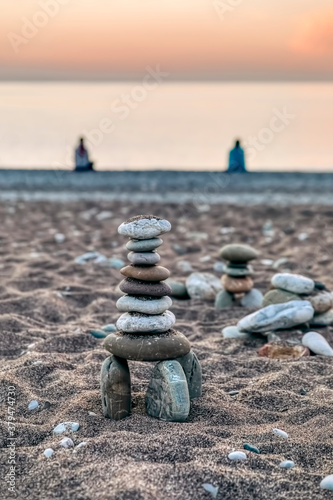Fototapeta Naklejka Na Ścianę i Meble -  Close-up of pebbles on beach at sunrise with meditating people - Cirali, Antalya Province, Turkey, Asia