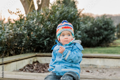 Fototapeta Naklejka Na Ścianę i Meble -  Toddler sitting on wooden bench and pointing