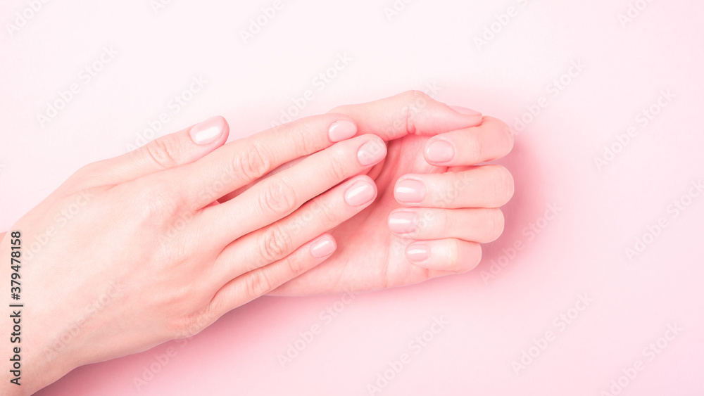 Beautiful female hands showing fresh cute manicure, skin and nail care concept, pink background