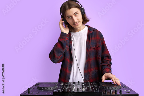 caucasian american young man listening music in headphones, stylish DJ with headset isolated over purple background.