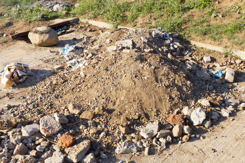 a pile of construction material rubble with cement, brick, sand and stone stacked on the sidewalk