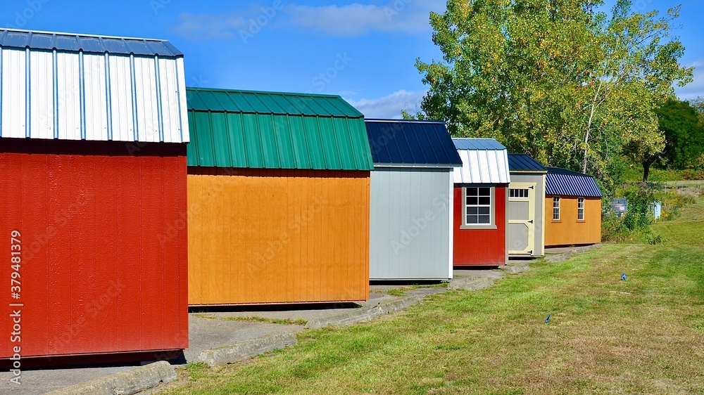 Colorful wooden sheds in a row. American shed is typically a simple, single-story roofed structure in a back garden or on an allotment that is used for storage, hobbies, or as a workshop. Colorful wooden sheds in a row. American shed is typically a simple, single-story roofed structure in a back garden or on an allotment that is used for storage, hobbies, or as a workshop.