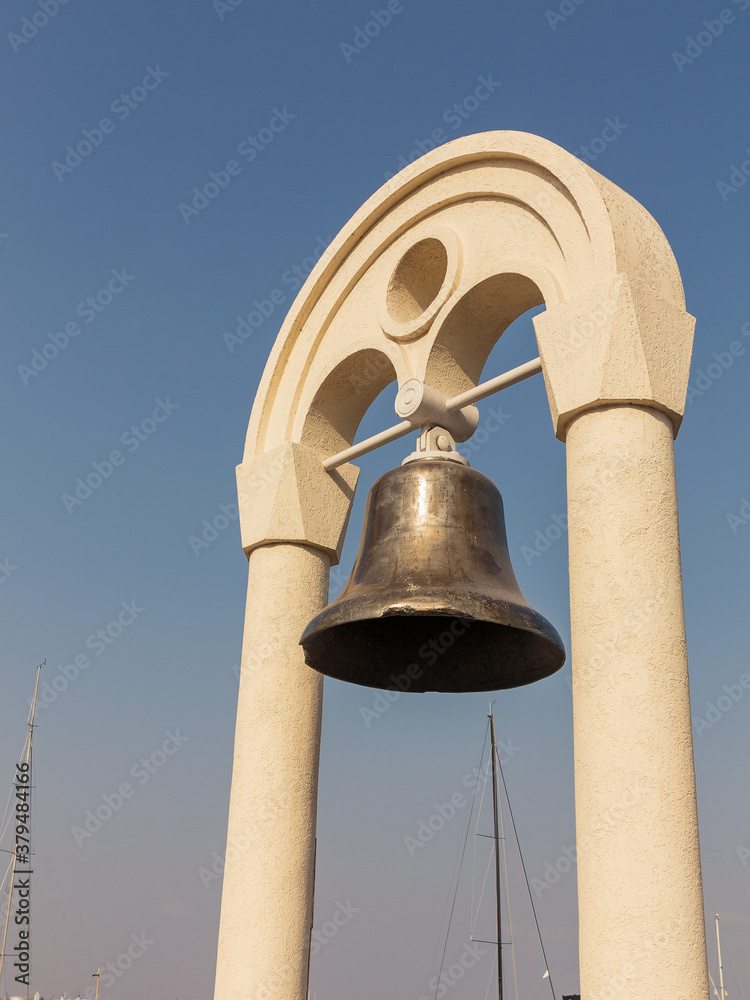 Bronze bell in the rays of the setting sun against a cloudless sky in the port of Odessa