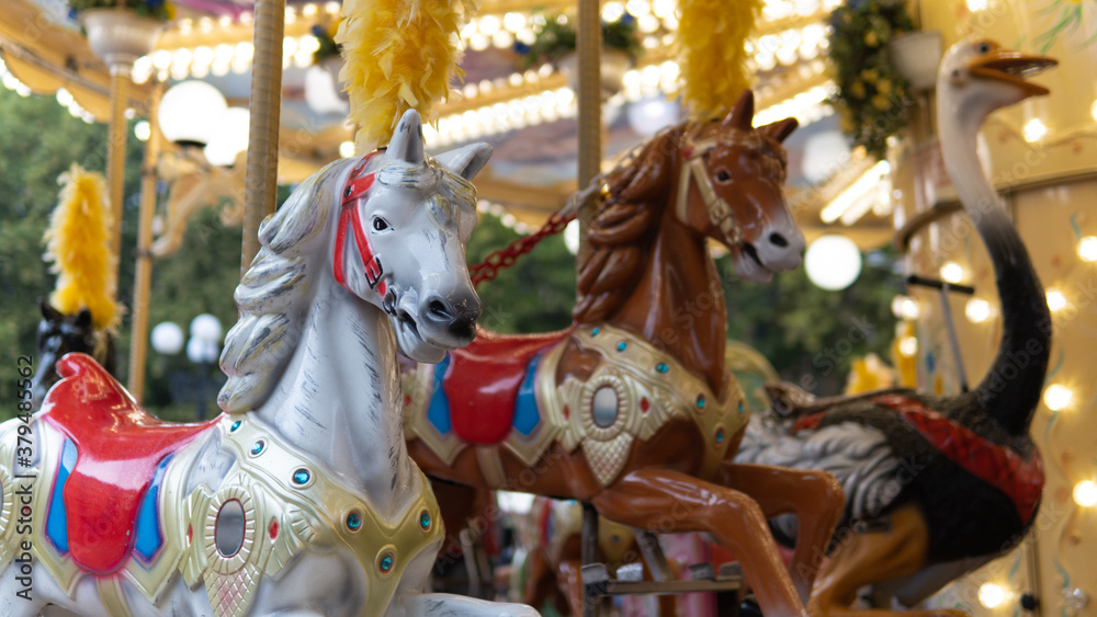 Two horses in the foreground of a carousel.