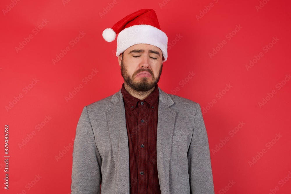 Young caucasian businessman wearing casual clothes standing over isolated red background has problems and difficulties, curves lower lip and closes eyes in despair, being in depression 