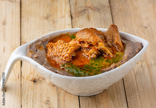Amala with ewedu and beef stew in a white ceramic bowl on a wooden background
