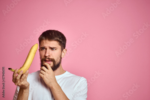 bearded man with banana in hand on pink background fun emotions model