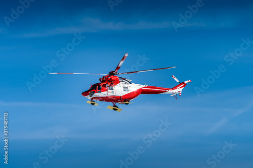 Red and White helicopter, rescue team or crew flying over Kasprowy Wierch and Swinica in High Tatra Mountains, providing rescue service, Poland