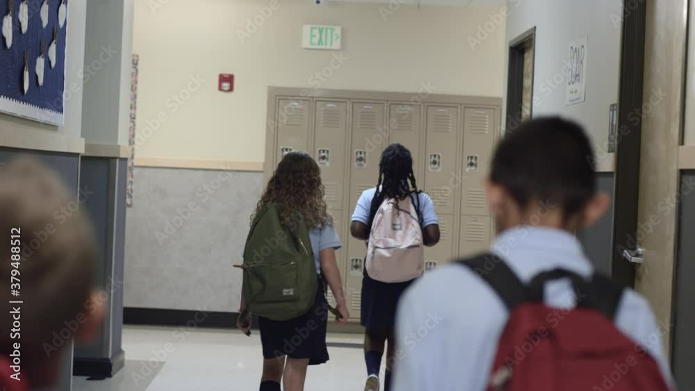 Diverse Primary and Elementary school children walk school hall in uniforms.