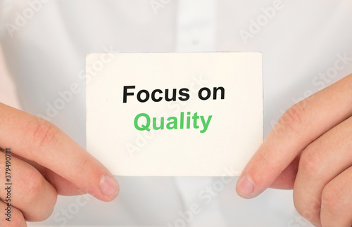 Man's hands take a card with words Focus on Quality, finance and business concept.