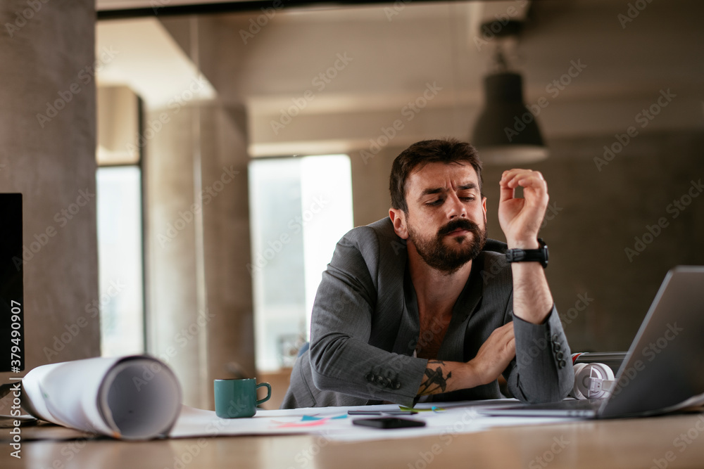 Young businessman working on projects. Tired businessman in suit working in the office. Young businessman working on projects. Tired businessman in suit working in the office.