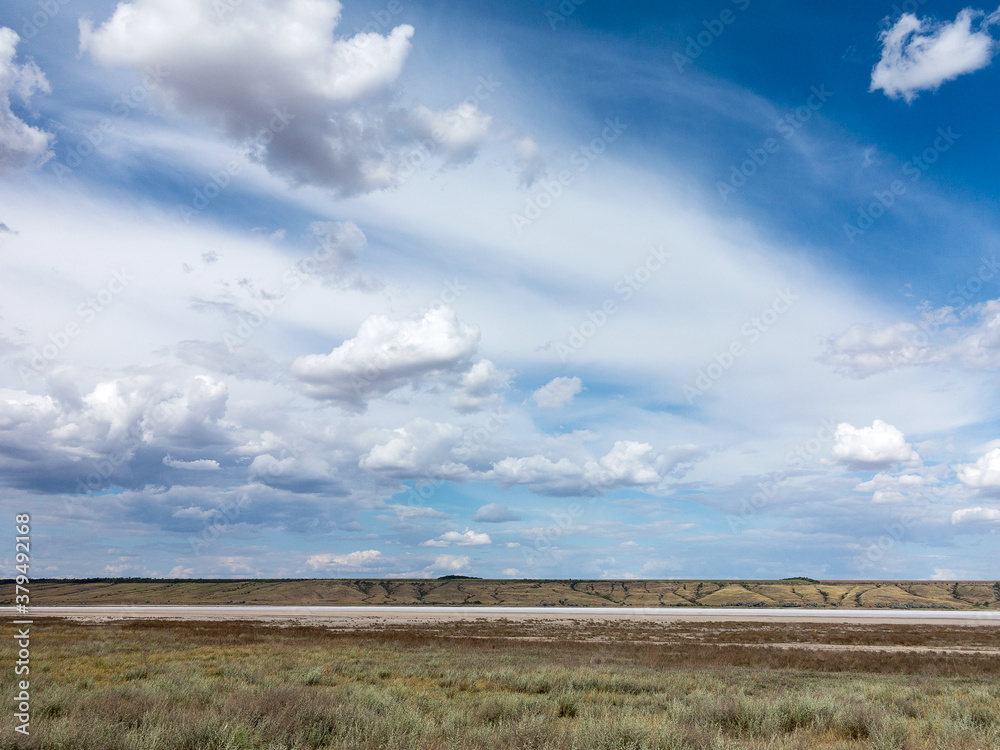 Obraz premium Rural landscape of blue sky in white clouds in the steppe. Dry and salt-covered Kuyalnitsky estuary near Odessa on a hot summer day