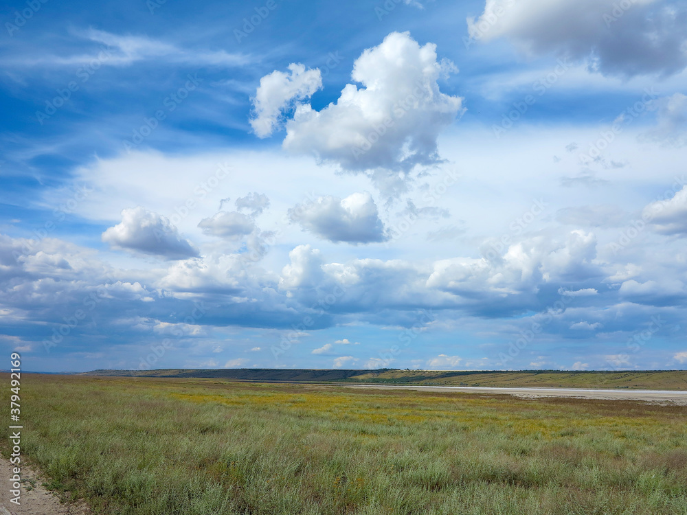 Rural landscape of blue sky in white clouds in the steppe. Dry and salt-covered Kuyalnitsky estuary near Odessa on a hot summer day
