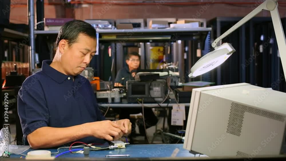 Asian electrical engineer assembling and testing computer component Asian electrical engineer assembling and testing computer component