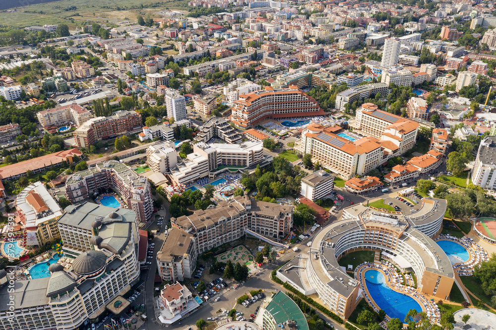 Obraz premium Suny Beach, Bulgaria - August 09, 2019: Aerial image a drone resort in Bulgaria on Black Sea coast. Many hotels and beaches with tourists, sunbeds and umbrellas. Sea travel destination. Travel