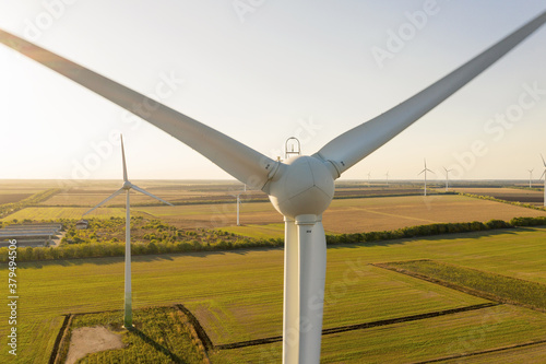 Aerial view on the windmills on the field, shot by drone. Renewal source of electricity. Wind turbines field new technology for clean energy on the field, sunset view with colorful twilight on sky.