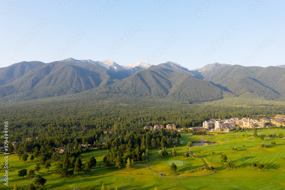 Aerial view from a drone. Stunning view of mountains and hotels of the mountain resort Bansko in morning at dawn. Beautiful landscape of sunrise in mountains is shot from drone. Travel 