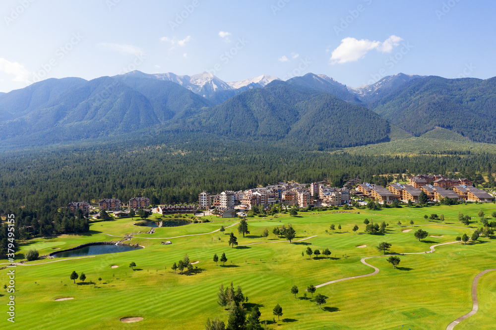 Aerial view from drone. Stunning view of mountains and hotels of mountain resort Bansko in morning at dawn. Beautiful landscape of sunrise in mountains is shot from drone. Travel and vacation concept.