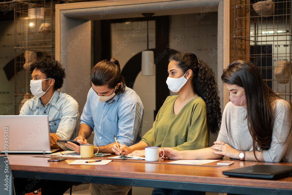 Serious brazilian group of entrepreneurs with face mask listening to meeting in office workspaceTeamwork, corporate, planning, strategy concept.. Serious brazilian group of entrepreneurs with face mask listening to meeting in office workspaceTeamwork, corporate, planning, strategy concept..