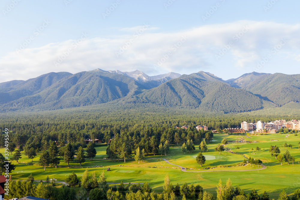 Obraz premium Aerial view from drone. Stunning view of mountains and hotels of mountain resort Bansko in morning at dawn. Beautiful landscape of sunrise in mountains is shot from drone. Travel and vacation concept.